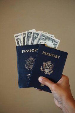 İçinde dolar banknotları olan iki Amerikan pasaportu. Fotoğraf seyahat ve para temalarını birbirine bağlıyor.