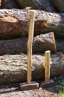 İki çekiç bir odun yığınının yanında dinleniyor, çalışmaya hazır. Ham, rustik ayar, ahşap işleme veya bölünme için kullanılan araçları vurgular.