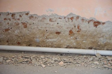 Renovation work removing an old wall in a house. Pieces of plaster and bricks reveal the wall structure, preparing the surface for further construction work.