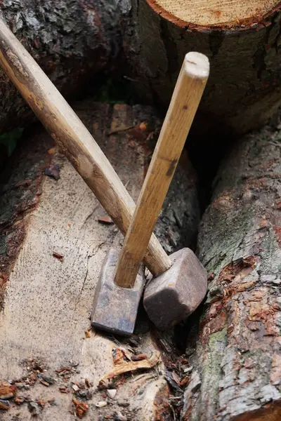 Tahta bir yüzeyde yan yana duran tahta saplı iki büyük çekiç. Kulpların ve metal kafaların görünür detayları.