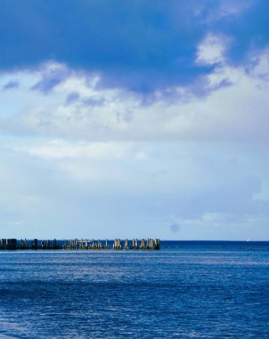 Baltık Denizi 'ndeki dalgalar parlak ve bulutsuz bir gökyüzünün altında uzaktan görülebilir. Gün ışığında sakin, doğal bir kıyı manzarası..