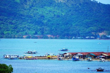 Birçok geleneksel bangka teknesi, Coron yakınlarındaki Palawan 'daki turkuaz suların üzerindeki stilt evlerin yakınına yanaştı..