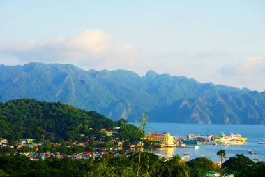 Büyük bir yolcu gemisi Palawan limanına yanaştı. Arka planda dağlar ve okyanus tropikal kasabanın yakınlarında pitoresk bir manzara yaratır..