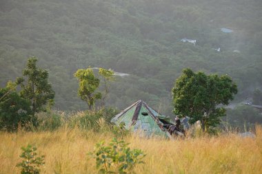 Palawan 'da bir dağ zirvesinde bulunan muşambadan yapılmış küçük bir sığınak geniş ormanlara ve sıradağlara bakıyor. Günbatımının sıcacık parıltısı gökyüzünü altın rengine boyuyor..