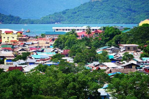 Coron kasabasının panoramasında binalar, deniz ve çevreleyen adaların manzarası resimli bir manzara sergiliyor..