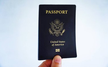 Amerikan pasaportu parlak, bulanık bir arka plan, seyahat ve kimlik belgesi üzerinde el ele tutuştu.