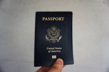 Bulanık arka plan, seyahat ve kimlik belgeleriyle elinde tutulan Amerikan pasaportu.