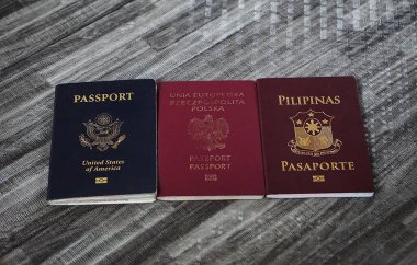 Üç pasaport Amerikan, Filipinli ve Polonyalı yan yana dizilmiş. Çoklu vatandaşlık ve uluslararası seyahat seçeneklerine örnek.