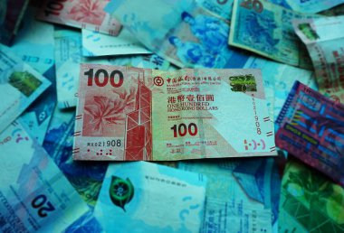 Kırmızı 100 dolarlık Hong Kong banknotunun yakın plan görüntüleri net grafik detayları, güvenlik özellikleri ve belirgin kağıt dokusu.