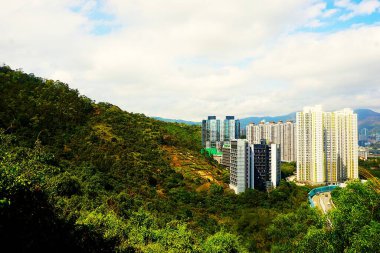 Hong Kong 'un solunda dağlar ve sağında da yüksek yerleşim yerleri olan gökdelenler. Doğayla şehir mimarisinin dinamik bir karışımı..