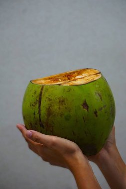 Kadınların elinde tutulan boş hindistan cevizi tarafsız bir arkaplanda. Tropikal meyve genellikle yemek ve doğal kozmetik ürünlerinde kullanılır..