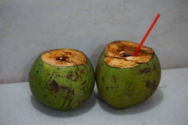 İki genç, yeşil hindistan cevizi açıldı, biri pipetli hindistan cevizi suyu gösteriyordu, elinde taze bir içecek vardı..