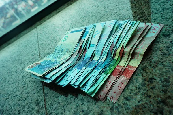Hong Kong dolar banknotları pencere eşiğine saçılmış, 20 dolarlık banknotlar belirgin bir şekilde görülüyor. Yumuşak ışıklandırma para biriminin ayrıntılarını ve renklerini vurgular.