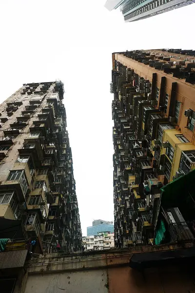 Hong Kong 'daki Canavar Binası' nın renkli fotoğrafı, aşağıdan çekildi. Renkli balkon ve pencerelerden oluşan sıralar geometrik, görsel olarak yoğun bir şehir labirenti oluşturur.