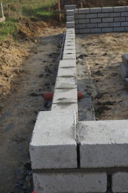 Cement blocks on pallets at a construction site, ready for building a house, organized materials, foundations and walls, realistic construction site view, construction work, construction crew.