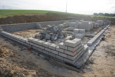 Cement blocks on pallets at a construction site, ready for building a house, organized materials, foundations and walls, realistic construction site view, construction work, construction crew.