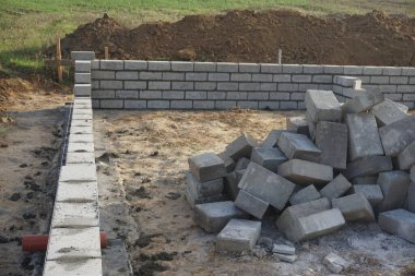 Cement blocks on pallets at a construction site, ready for building a house, organized materials, foundations and walls, realistic construction site view, construction work, construction crew.