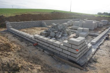 Cement blocks on pallets at a construction site, ready for building a house, organized materials, foundations and walls, realistic construction site view, construction work, construction crew.