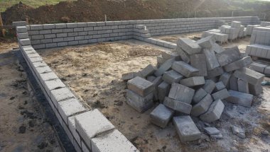 Cement blocks on pallets at a construction site, ready for building a house, organized materials, foundations and walls, realistic construction site view, construction work, construction crew.