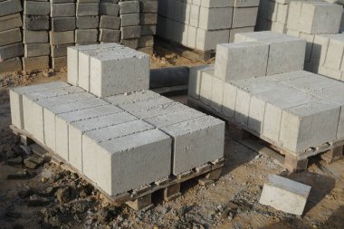 Cement blocks on pallets at a construction site, ready for building a house, organized materials, foundations and walls, realistic construction site view, construction work, construction crew.