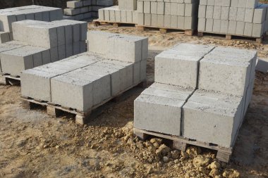 Cement blocks on pallets at a construction site, ready for building a house, organized materials, foundations and walls, realistic construction site view, construction work, construction crew.