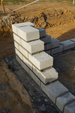Cement blocks on pallets at a construction site, ready for building a house, organized materials, foundations and walls, realistic construction site view, construction work, construction crew.
