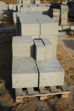 Cement blocks on pallets at a construction site, ready for building a house, organized materials, foundations and walls, realistic construction site view, construction work, construction crew.