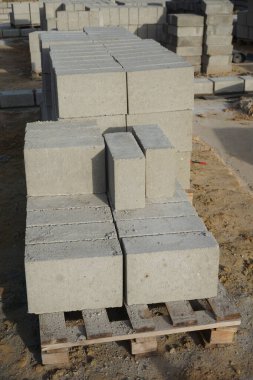Cement blocks on pallets at a construction site, ready for building a house, organized materials, foundations and walls, realistic construction site view, construction work, construction crew.