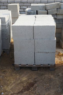 Cement blocks on pallets at a construction site, ready for building a house, organized materials, foundations and walls, realistic construction site view, construction work, construction crew.