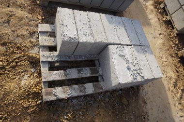 Cement blocks on pallets at a construction site, ready for building a house, organized materials, foundations and walls, realistic construction site view, construction work, construction crew.