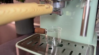 Taze demlenmiş espresso akıntıları bir shot bardağına dökülüyor. Süreç, içeceklerde daha fazla kullanılmak üzere kahve hazırlama, aroma, tat ve barista sanatının altını çizmeyi gösteriyor..