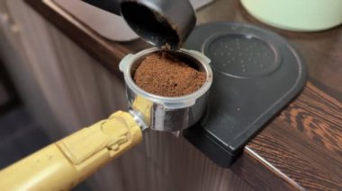 Video, portatif filtreye öğütülmüş kahve doldurma ve sıkıca doldurma sürecini gösteriyor. Barista 'nın özel hazırlama adımlarının yakından görüntüsü..