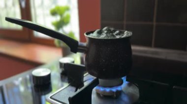 Kaynar suyu yanan bir gaz ocağına taşan bir merhem. Köpüren su aleve sıçrar ve bir insan güvenlik için çabucak ocağı kapatır..