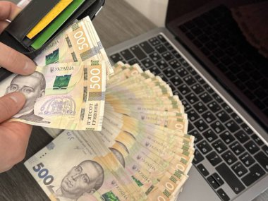 Bir kişi bir cüzdan tutar ve banknotları sayar. Masaya daha fazla para saçılır. Sahne, kişisel finans, bütçe ve para yönetimini simgeliyor..