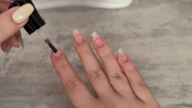 Bir kadın kendi tırnaklarına jel oje sürüyor ve iyileştirmek için elini ultraviyole lambanın altına sokuyor. Ev manikürü, güzellik endüstrisi ve tırnak bakımı konsepti..