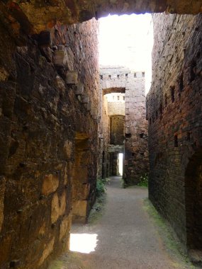 Kaba yontulmuş granit bloklar tarafından çerçevelenmiş eski bir kalenin kalın duvarlarına yerleştirilmiş yıpranmış taş bir kapı. Dar kemerli giriş karanlık, kapalı bir taş odaya açılıyor. İçi ancak doğal ışıkla aydınlanıyor..