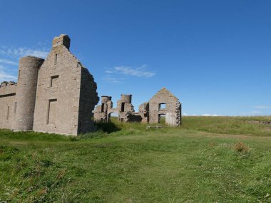 Slains Kalesi, İskoçya 'nın kuzeydoğu kıyısındaki engebeli deniz kayalıklarının tepesine çarpıcı bir şekilde tünemişti. Tarihi şatonun yıpranmış taş duvarları, yemyeşil otlar ve vahşi kıyı bitkileriyle çevrili derin mavi Kuzey Denizi 'ne tepeden bakar.