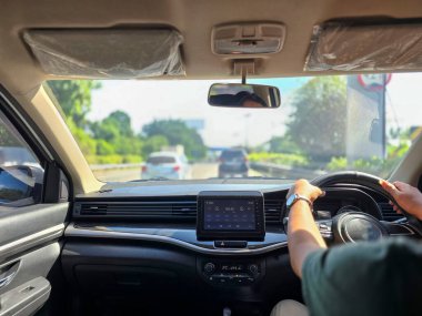 Şehir Jakarta 'sında güneşli hava ve mavi gökyüzü ile araba süren bir kişi.