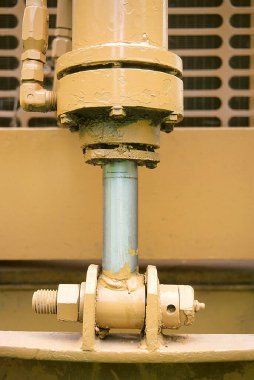 İçinde metal bir çubuk ve sürgülü flanş bulunan sarı boyanmış bir silindir.