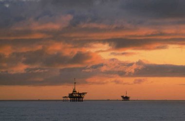 Dramatik Günbatımında Offshore Petrol Sondaj Platformlarının gerçekçi bir resmi