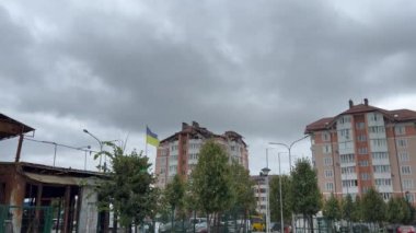 Bulutlu gökyüzü ve Ukrayna bayrağı. Ukrayna 'da hasar görmüş ve yanmış bir şehir, Kyiv yakınlarında. Ukrayna 'da Savaş. 