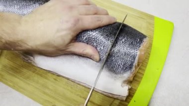 Adam, lezzetli yemekler hazırlamak için balığı bıçakla parçalara ayırıyor. Tahta kesme tahtasıyla. Aşçı taze balık somon bifteği keser.. 