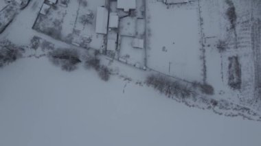 Kışın köyün insansız hava aracı görüntüsü, binanın tepesinde kar. Sisli hava.