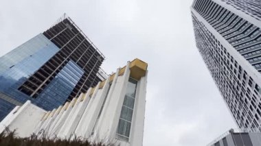 Blending old and new architecture. A city with mixed architecture- sovet union building together whith high modern towers. Low Angle View. tilt up from street to sky.