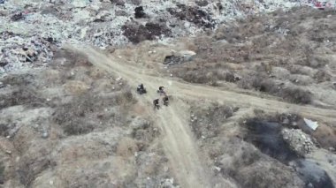 Motosikletliler ülkeyi boydan boya bisikletle geziyor ve bir tanesi de çöplüğün yakınındaki bir ATV 'de. Hava görünümü