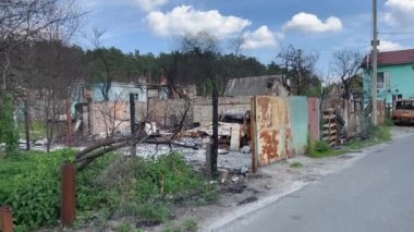 Savaşın yok ettiği, Ukrayna 'da hava saldırısından sonra hasar gören ve yanan bir ev. 2022 'deki Rus saldırısının korkunç sonuçları. Çiçek açan ağaçlar ve yanan eve karşı bulutlu mavi gökyüzü..
