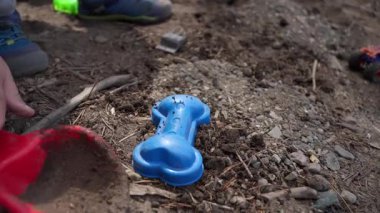 Kırmızı kürek ve mavi kum kalıbıyla oynayan bir çocuğun yakın çekimi. Açık havada çocukluk eğlencesi.