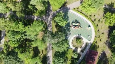 Yoğun yeşil bir orman, futbol sahası, dolambaçlı patikalar üzerinde uzun tepeden aşağıya insansız hava aracı uçuşları, merkezinde kırmızı çatılı bir çardak bulunan ahşap köprüsü olan huzurlu göl.. 