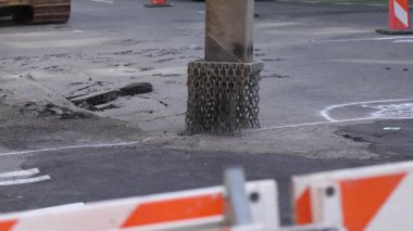 Hidrolik kırıcının yavaş hareketi asfaltı un ufak ediyor. Aracın etrafındaki zincirler çarpmanın etkisiyle kaldırım parçaları dağılır. Güçlü endüstriyel ekipmanlar. Yol yapımı.