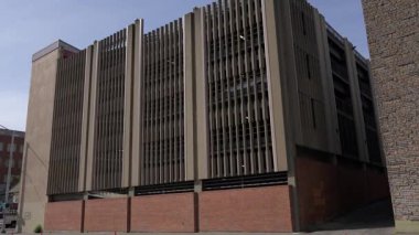 Dikey beton çatallar ve kırmızı tuğla tabanlı modern çok katlı bir otoparkın dış görünüşü. Açık bir günde, kentsel, altyapı ve mimari temalar için uygun bir şekilde ele geçirildi.